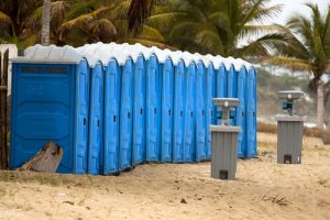 line of porta potties in the beach with a portable hand washing station